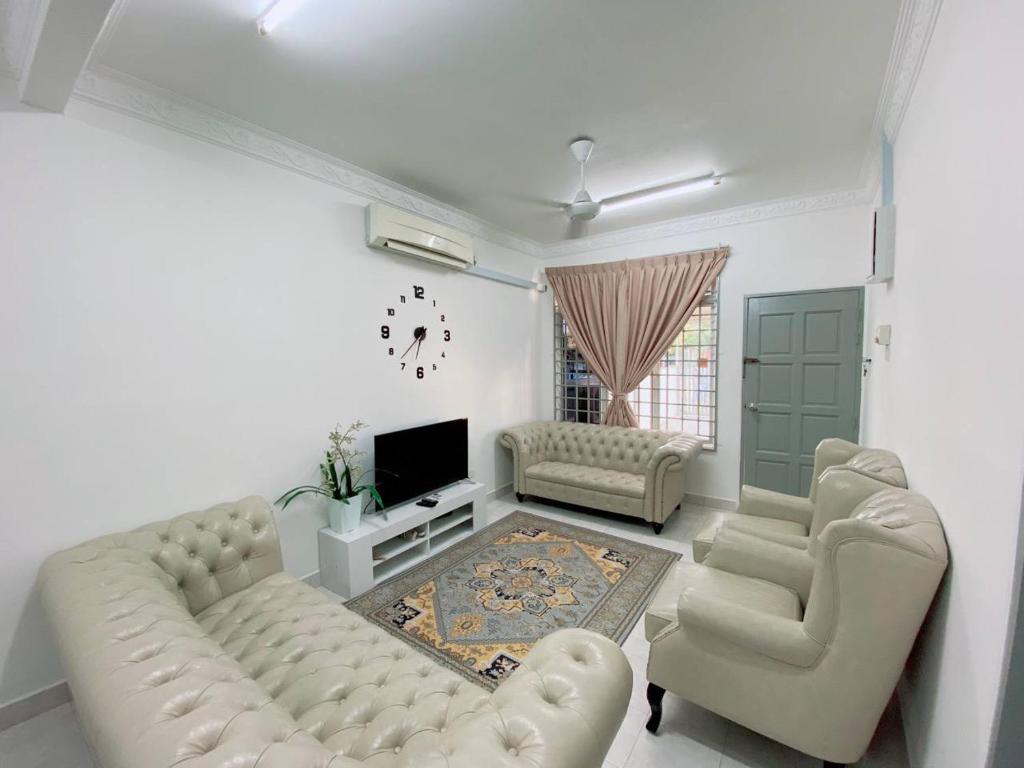 a living room with a couch and chairs and a television at Grandmaa Homestay, Seberang Takir in Kuala Terengganu