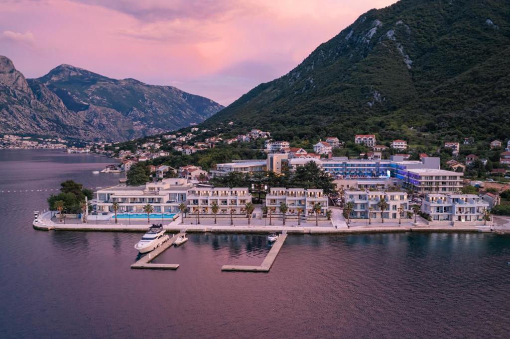 um grupo de edifícios sobre a água com montanhas em Hyatt Regency Kotor Bay Resort em Kotor