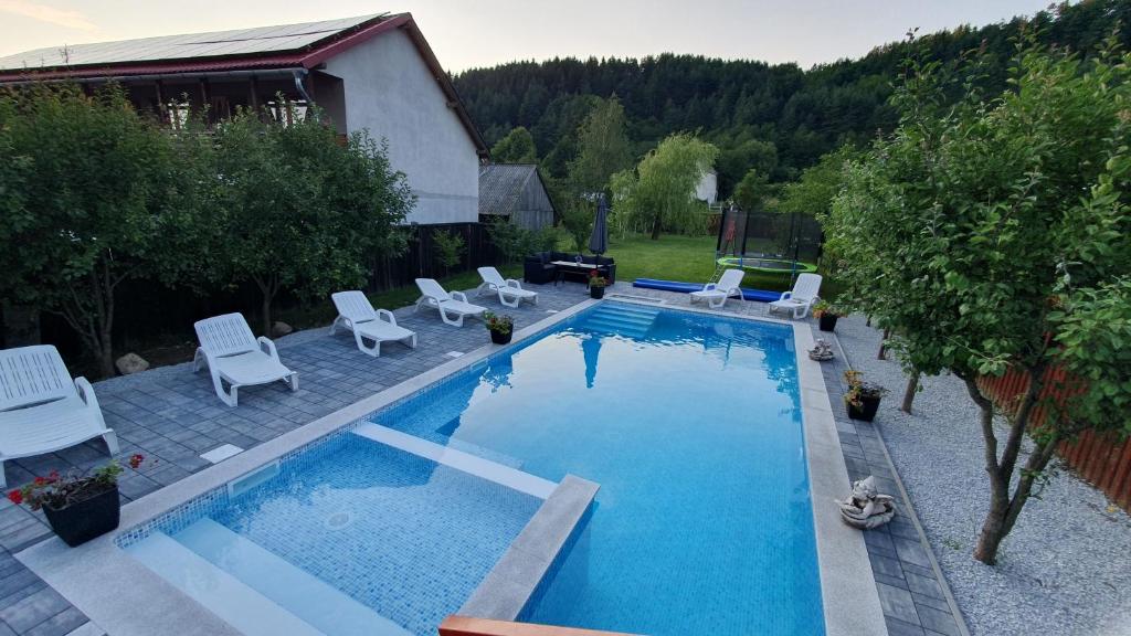 a swimming pool with white chairs at Ati&Hanna in Praid