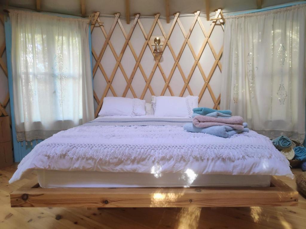 um quarto com uma cama com lençóis brancos e almofadas em Love Frequency - יורט קסום במתת em Mattat