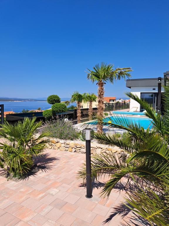 een resort met een zwembad en palmbomen bij Villa Belissima Vista Mare in Selce
