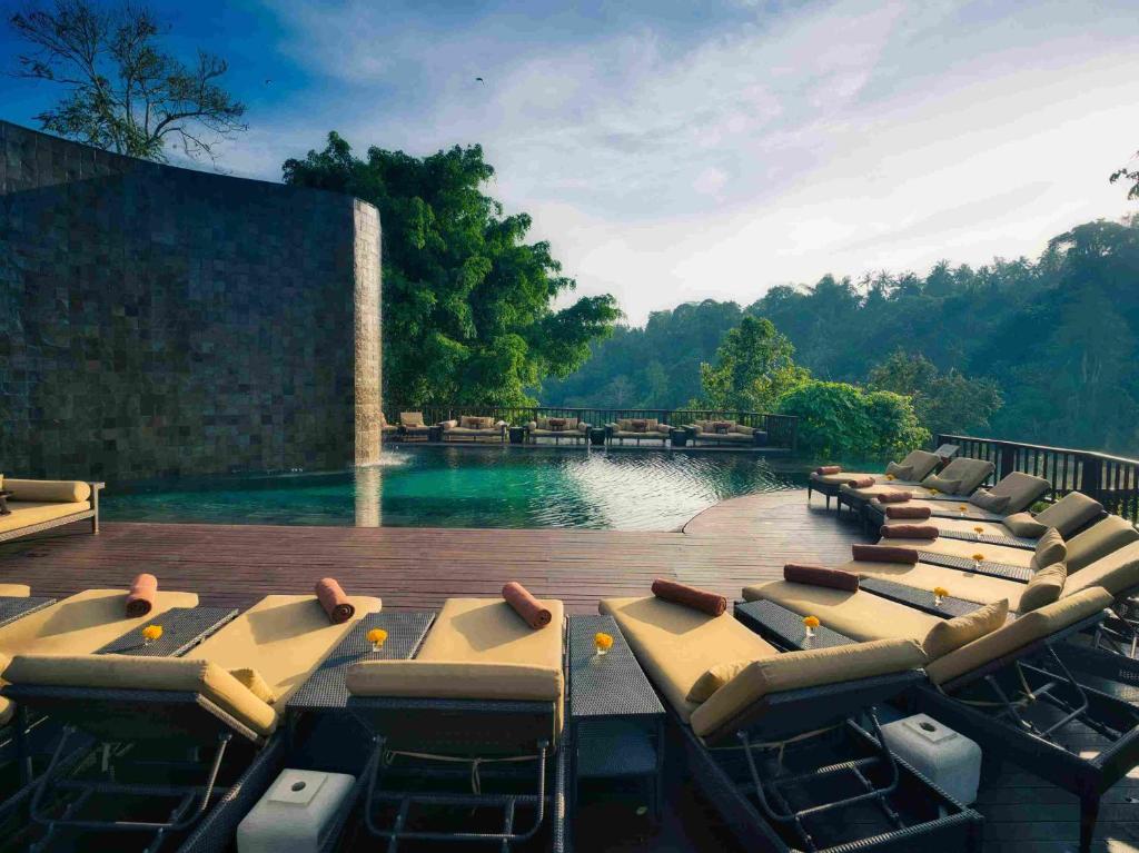 a row of tables and chairs on a pool of water at Hanging Gardens of Bali in Payangan