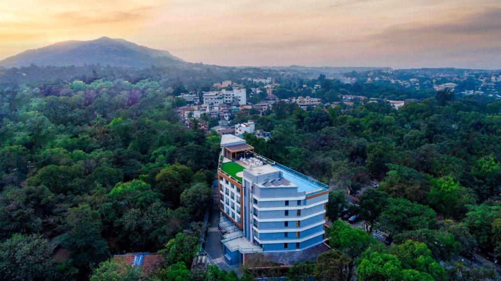 a tall building in the middle of a forest of trees at Regenta SGS Greenotel - Lonavala in Lonavala