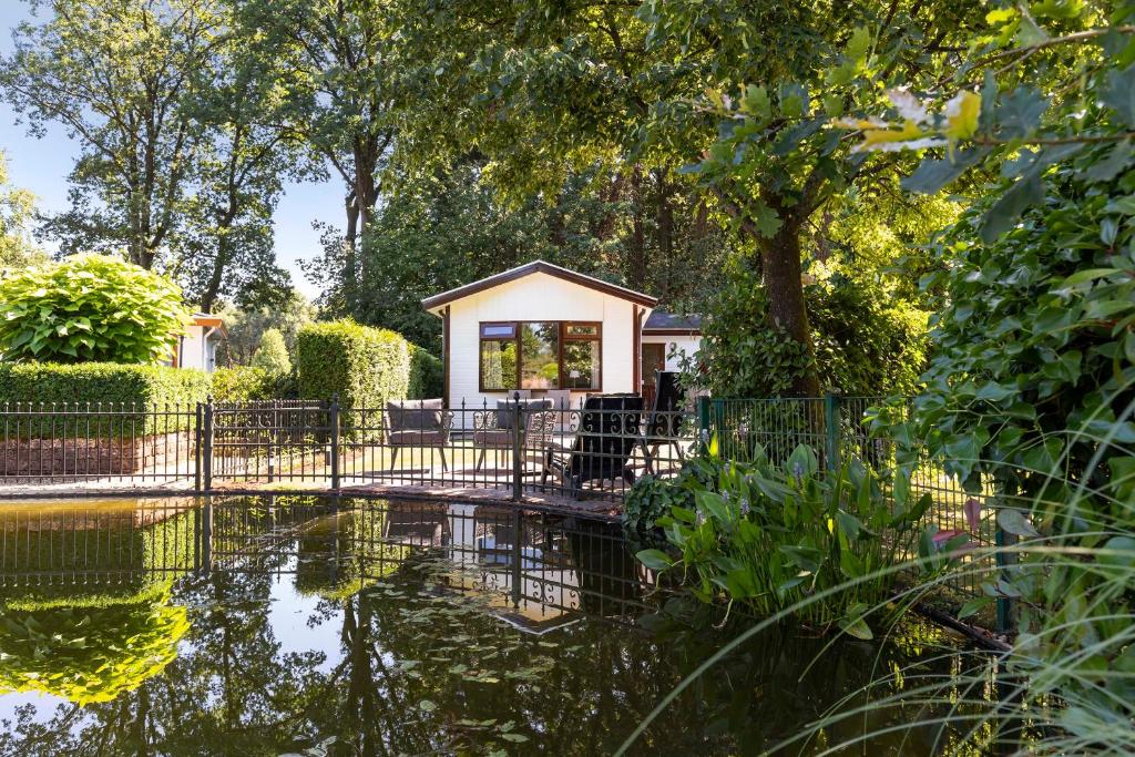 ein Haus mit einem Teich davor in der Unterkunft Huize Bosrijk aan het water in Kootwijk