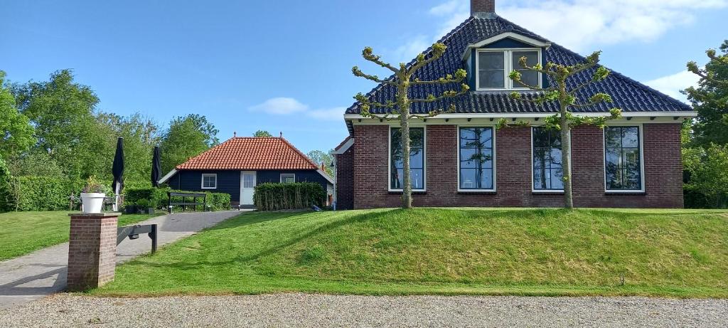 a house with a green lawn in front of it at B&B Stations Koffiehuis in Molkwerum