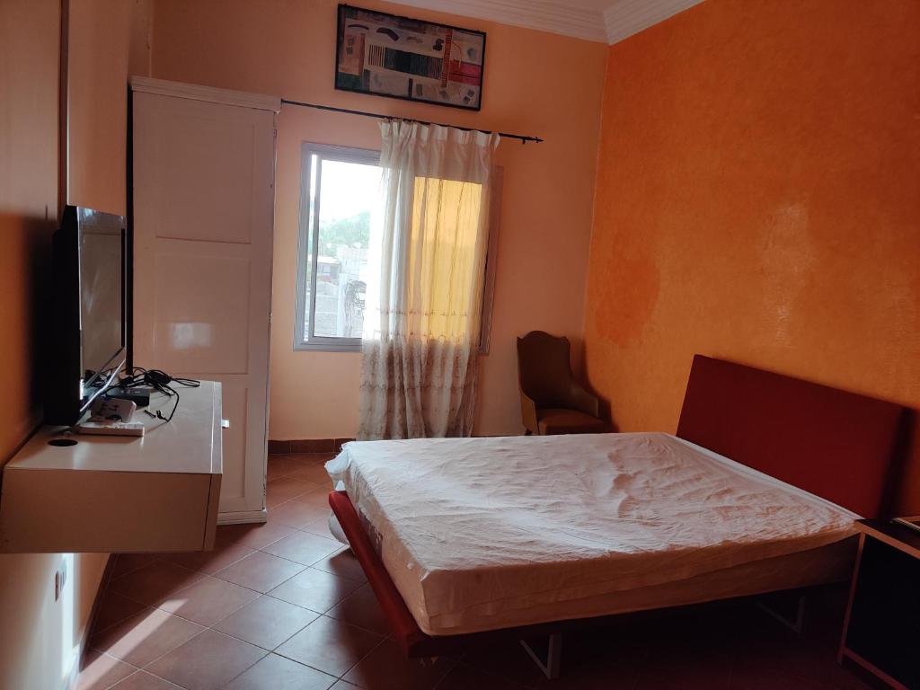 a bedroom with a bed and a desk and a window at Keur Magatte in Saint-Louis