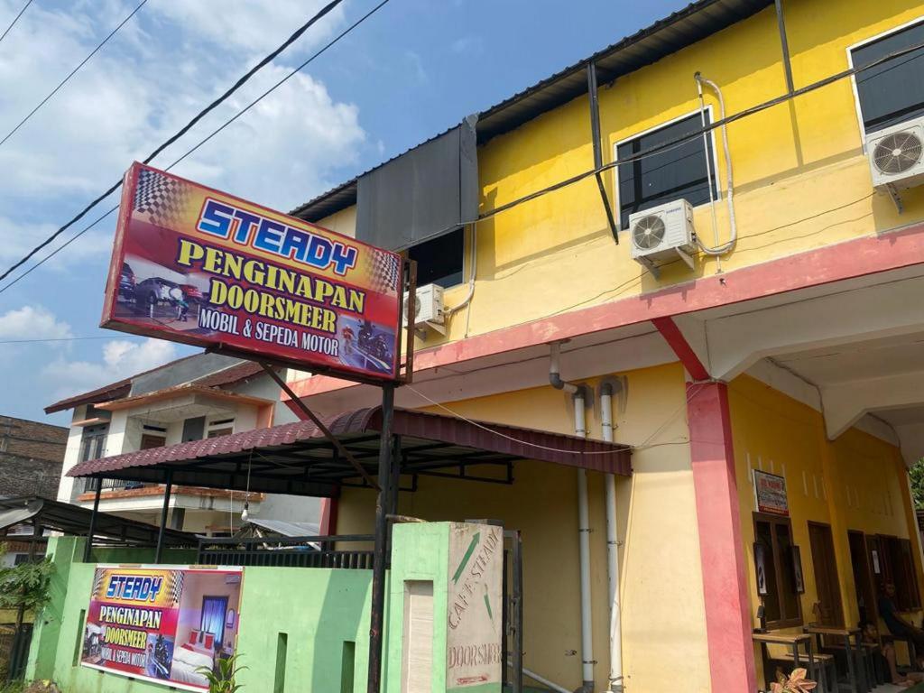 un bâtiment avec un panneau devant lui dans l'établissement Penginapan Steady Mitra RedDoorz, à Pematang Siantar