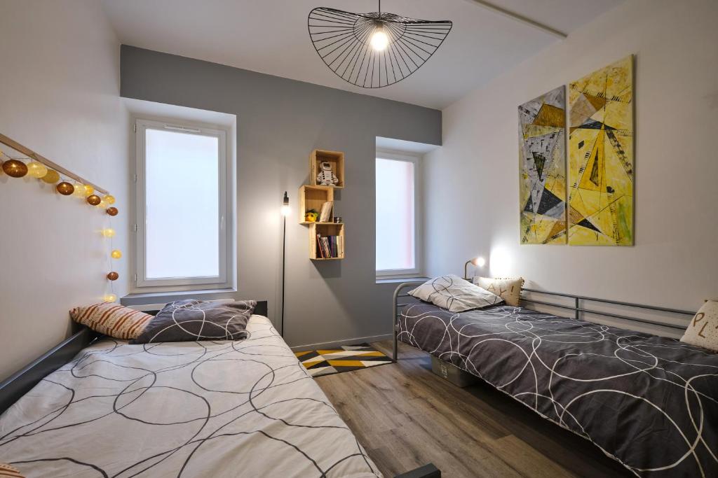 duas camas num quarto com duas janelas em Magnifique T3 centre ville avec WIFI RDC em Limoux
