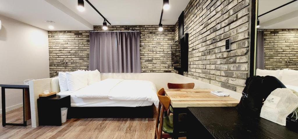 een slaapkamer met een bed en een bakstenen muur bij Daon Hotel Gimhae Injae in Gimhae