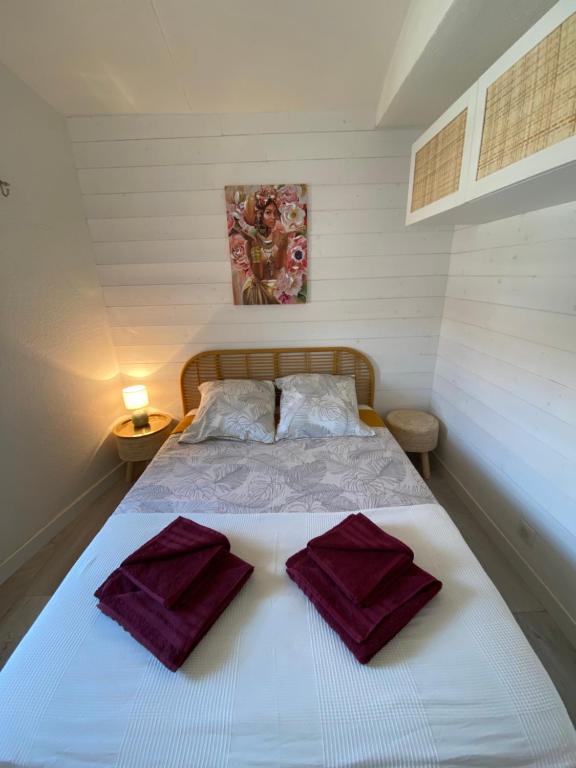 Un dormitorio con una cama con toallas moradas. en Appartement Duplex Climatisé Le Trident, en Saintes-Maries-de-la-Mer