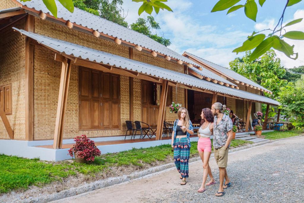 a group of three people standing outside of a house at Society House Luxury Hostel in Pai