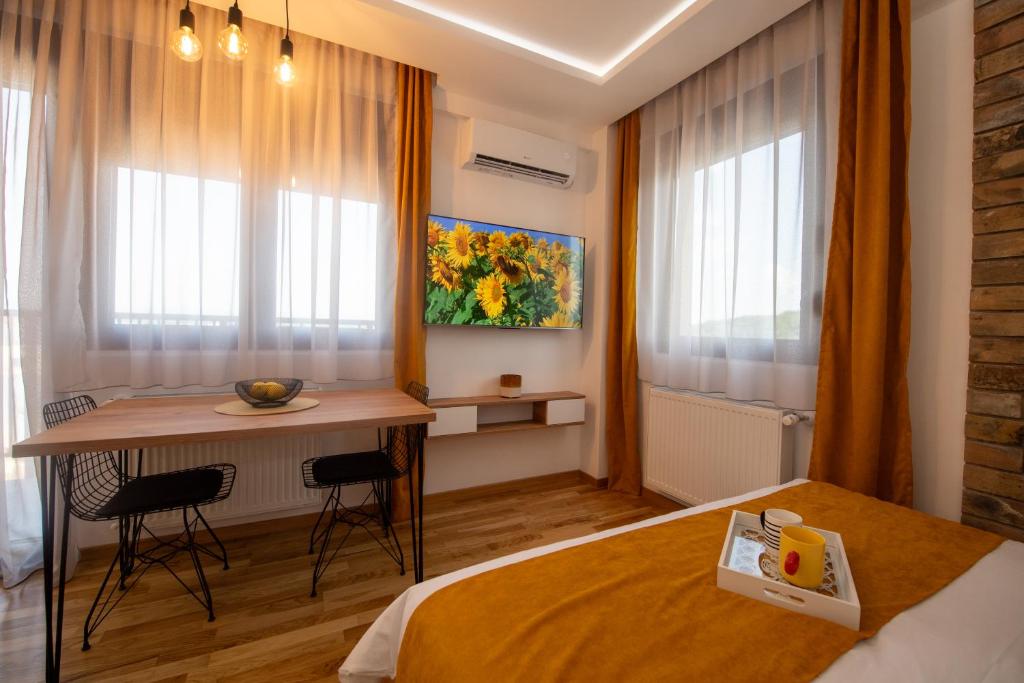 um quarto com uma cama, uma mesa e janelas em Lux Apartman Sunce em Jagodina