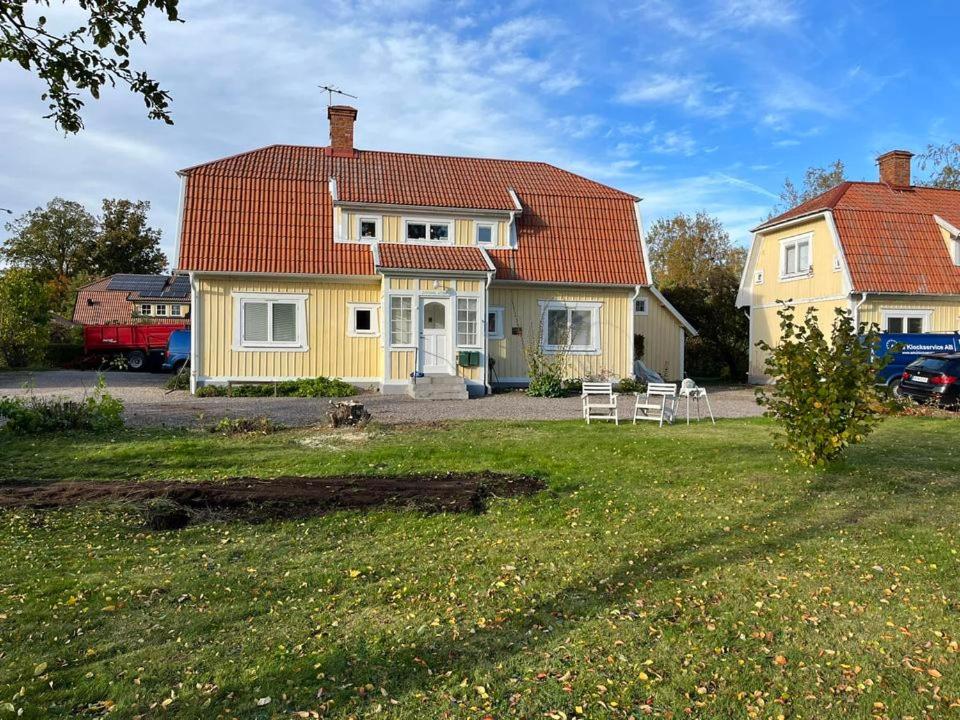 una casa amarilla con techo rojo en un patio en Lovisas Stuga, en Vadstena