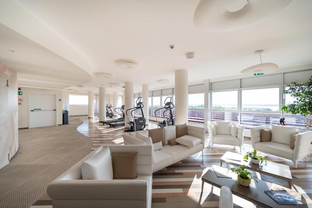 a living room with white furniture and treadmills at Laguna Park Hotel 4Superior in Bibione