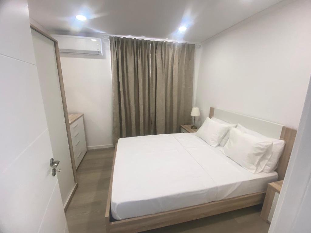 a white bedroom with a white bed and a window at DOCE DREAM GUEST HOUSE in Santa Iria da Azóia