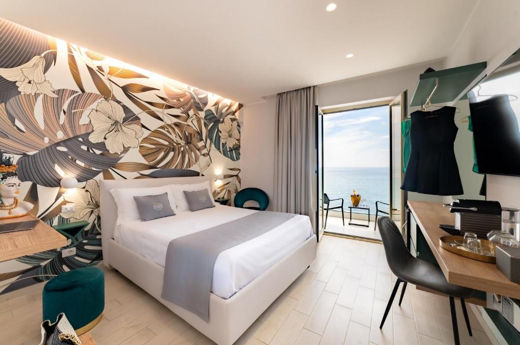 a bedroom with a bed and a desk and a balcony at Naxos Marina Bay in Giardini Naxos