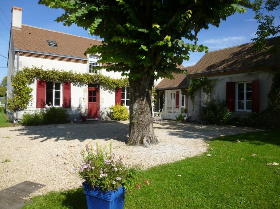 una casa con un árbol en el patio delantero en Les volets rouges en Sémoy