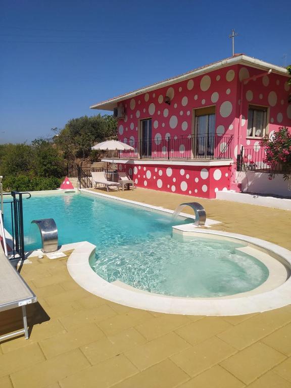 a swimming pool in front of a red building at B&B Vento di Scirocco in Favara