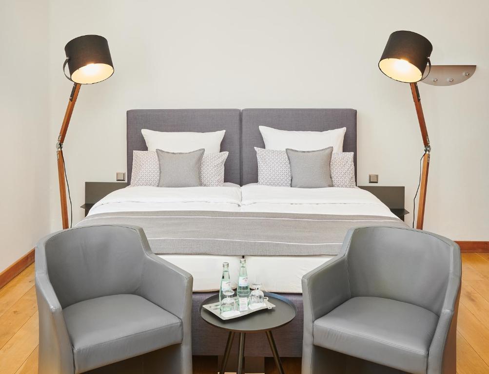 a bedroom with a large bed with two chairs at Hotel Mutterhaus Düsseldorf in Düsseldorf