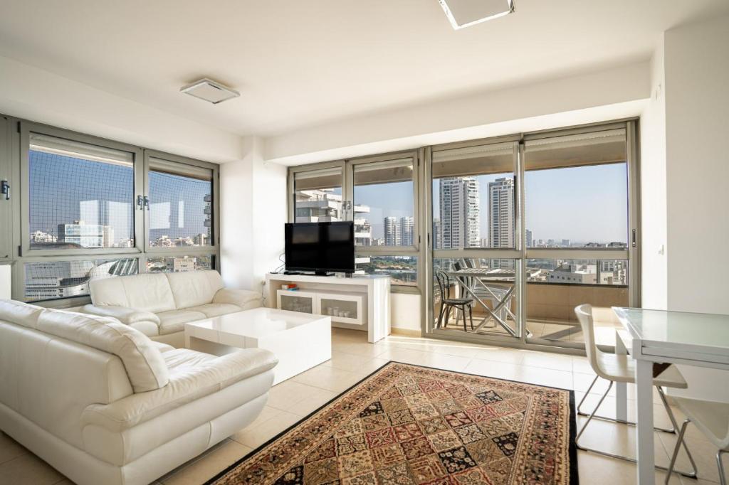 una sala de estar con muebles blancos y ventanas grandes. en Luxury Apartments Blue Wave en Ashdod