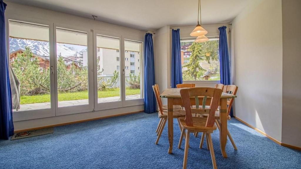 a dining room with a table and chairs and windows at Casa Cresta A31 in Arosa