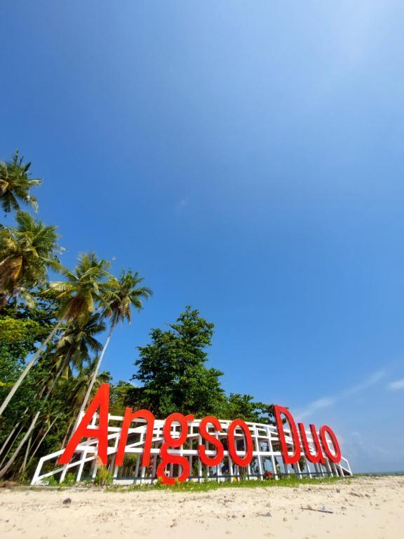 a large sign on a beach with palm trees at Angso Duo Resort in Pariaman