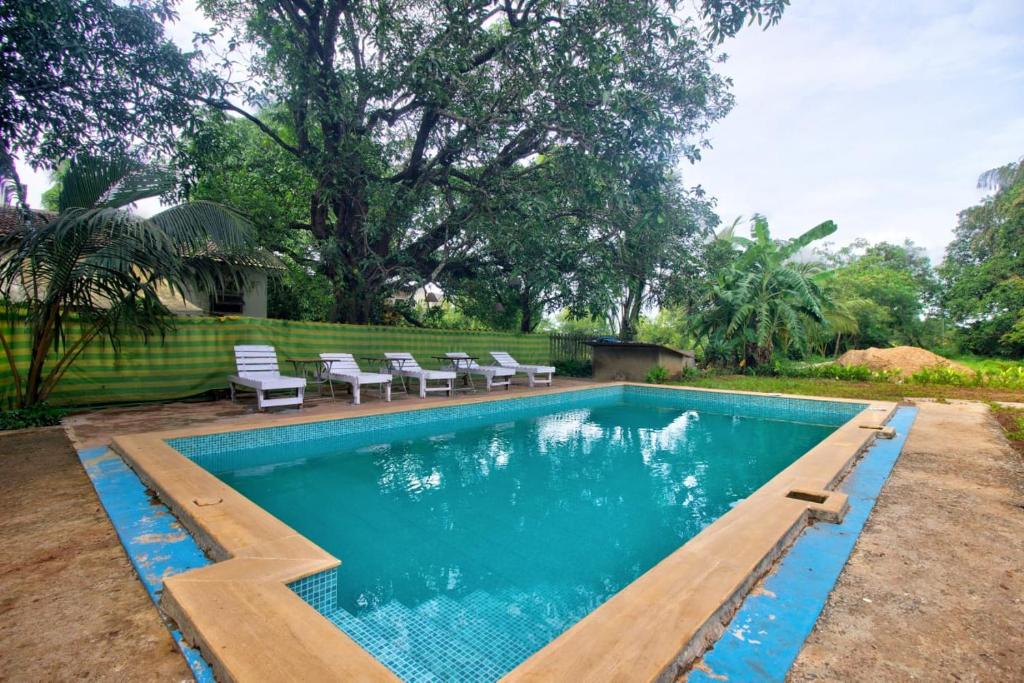 a swimming pool with benches and chairs in a yard at Goa Garden 6BHK Villa with Private Pool Near Baga in Marmagao