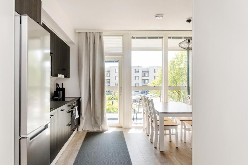 a kitchen and dining room with a table and a window at Kotimaailma Apartments Loimu II with Private Sauna in Oulu