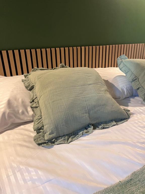 Green ruffled throw pillow on white-striped bedding against slatted wooden headboard and green wall.