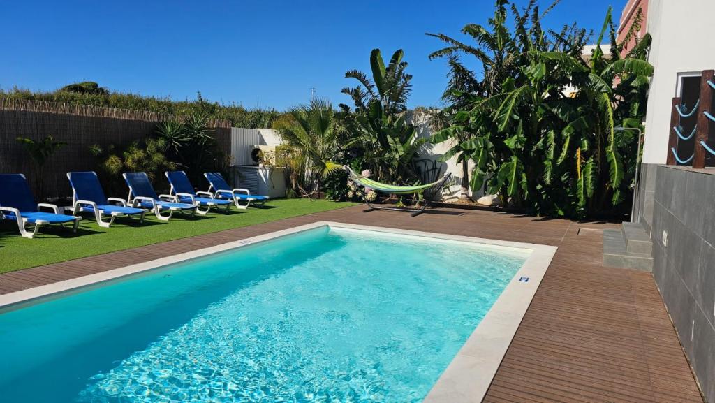 a swimming pool in a backyard with chairs and a swimming pool at Seabreeze- Vista Mar-Vivenda Privada-Near Ericeira in São Pedro da Cadeira