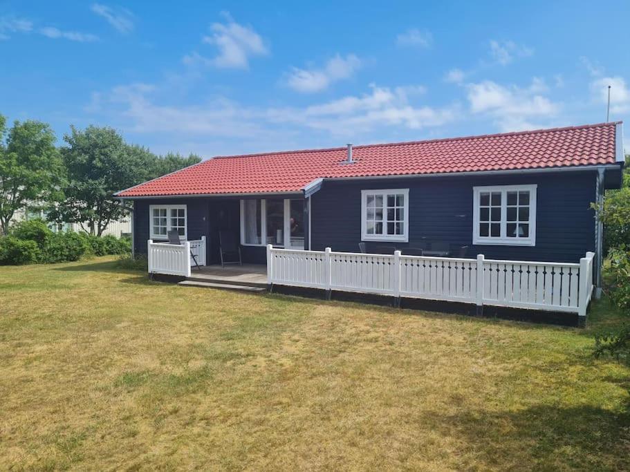 una casa azul con una valla blanca y un patio en Trevlig och havsnära stuga, en Glommen