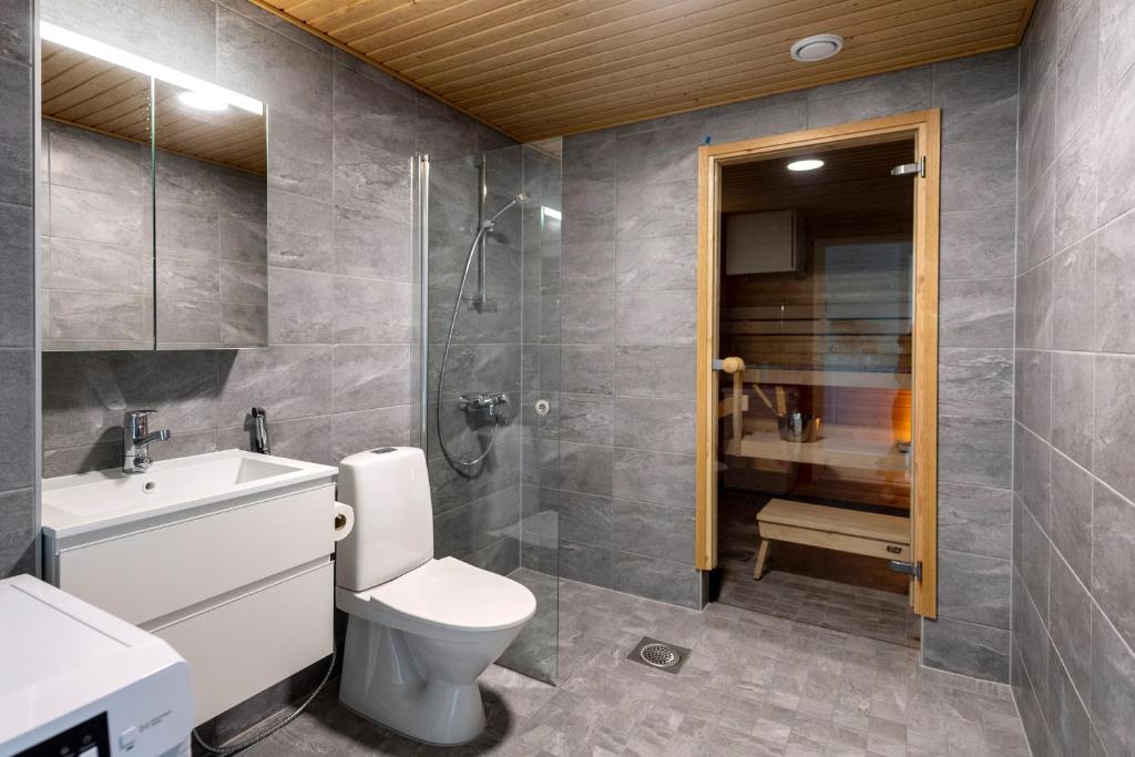 a bathroom with a toilet and a sink and a shower at Kotimaailma Apartments Loimu I in Oulu
