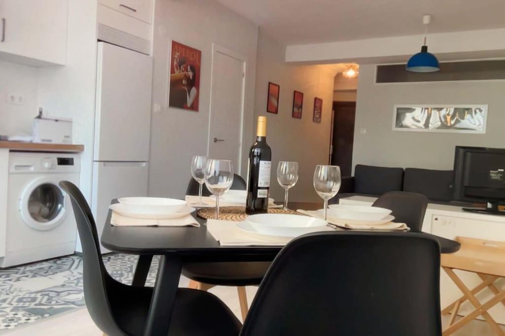 a dining room table with glasses and a bottle of wine at Apartamento Torre de Hércules in A Coruña