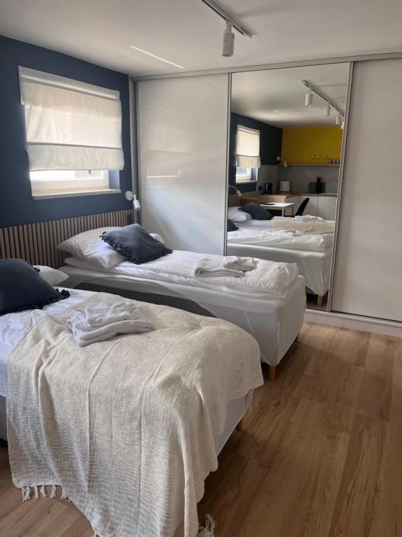 Twin beds neatly made with towels, dark accent wall, mirrored closet reflecting kitchenette.