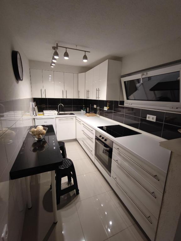 a kitchen with white cabinets and a black table at APARTMANI VIJEĆNICA in Sarajevo