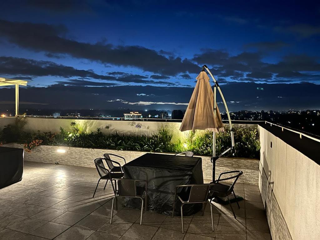 eine Terrasse mit einem Tisch, einem Sonnenschirm und Stühlen in der Unterkunft Tania Suites 2 bed Perry West in Nairobi