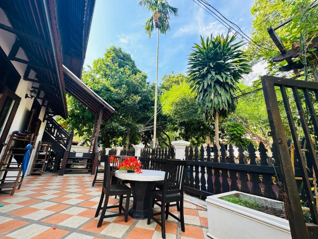 un patio con mesa, sillas y árboles en Thatsaphone Hotel, en Luang Prabang