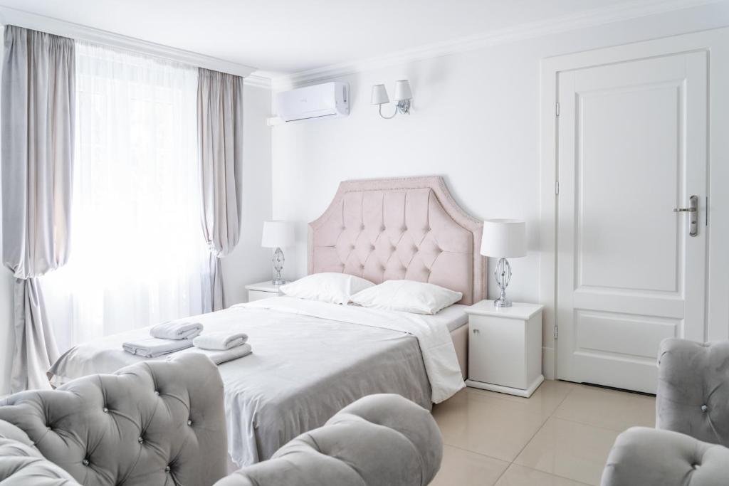 a white bedroom with a large bed and two chairs at Fryderyk in Krynica Morska