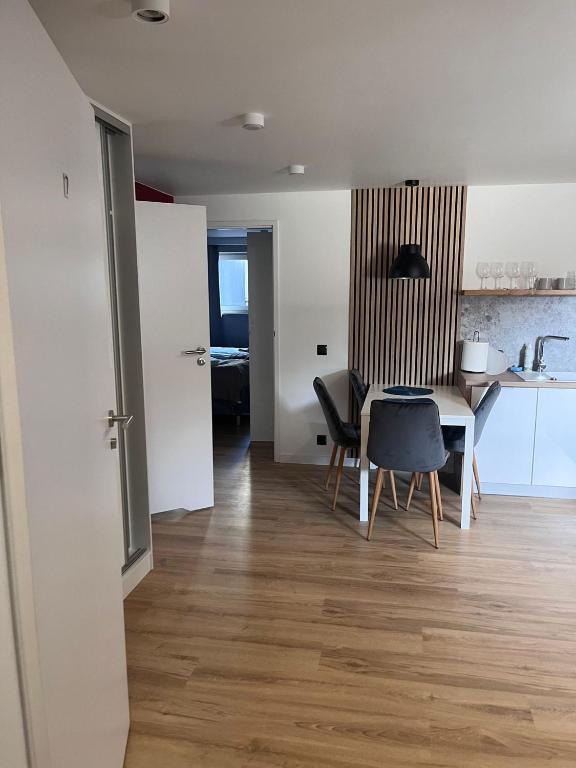 Entrance view into apartment showing dining table, slatted wall panel, pendant lamp, open interior doors.