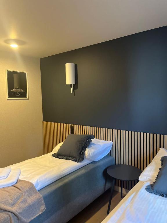 Twin bedroom with two single beds, navy accent wall and small round bedside table.