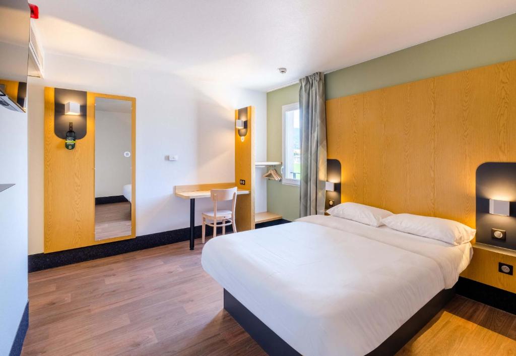B&B HOTEL Cannes La Bocca Plage في كان: غرفة الفندق بسرير كبير ومكتب