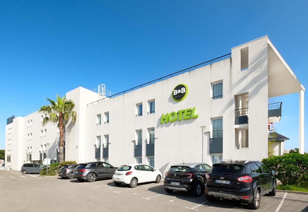 un hôtel avec des voitures garées devant lui dans l'établissement B&B HOTEL Cannes La Bocca Plage, à Cannes