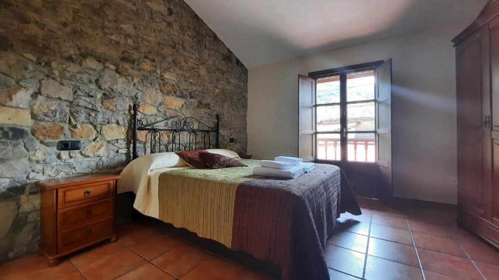 sypialnia z łóżkiem i kamienną ścianą w obiekcie Casa rural La Casina w mieście Sariego