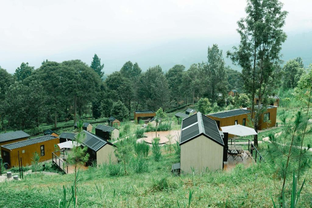 Bobocabin Gunung Mas, Puncak في Tagalbato: مجموعة منازل في ميدان به اشجار