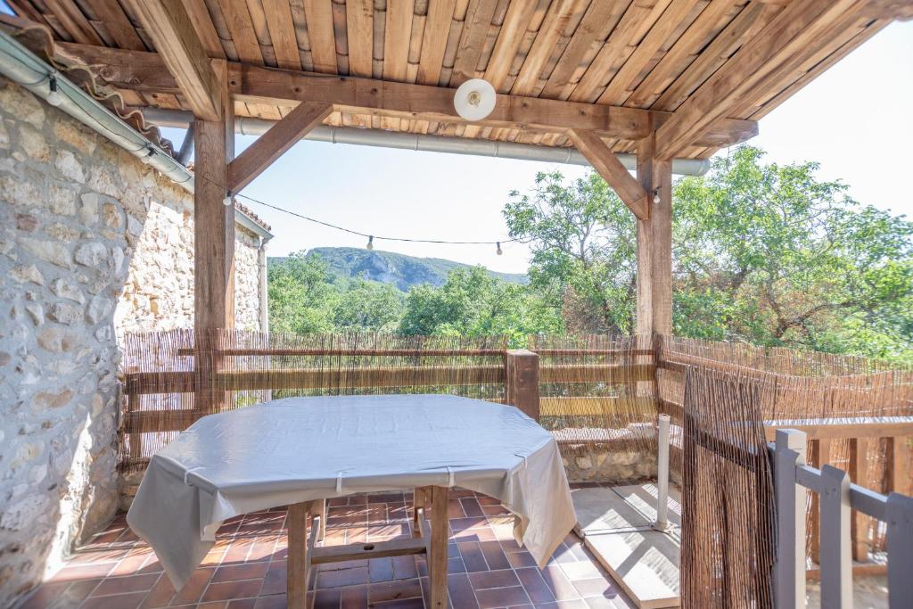 uma pérgola de madeira com uma mesa num pátio em Maison L'Ibie - Avec vue sur la montagne em Vallon-Pont-dʼArc