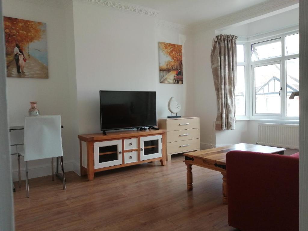 a living room with a flat screen tv on a wooden table at Lovely 3 Bedrooms Flat Near Romford Station With Free Parking in Romford