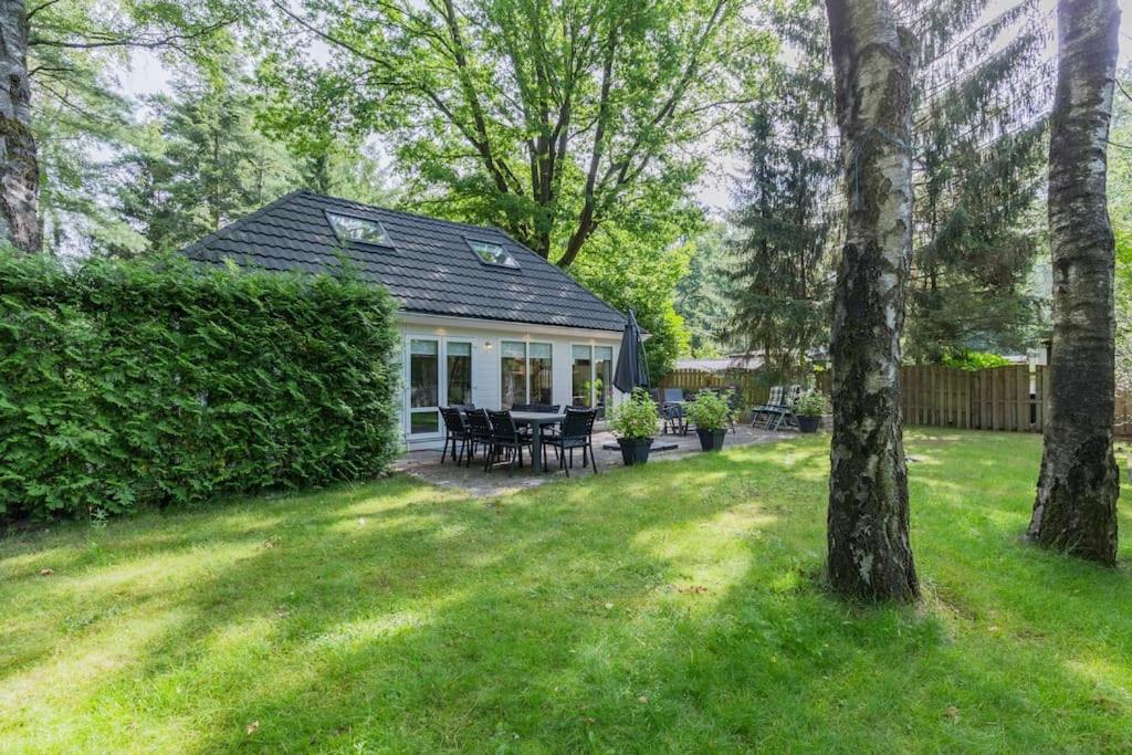 een huis met een tuin met een tafel en stoelen bij 8 pers vakantiehuis met natuur- sauna en bubbelbad in Diessen