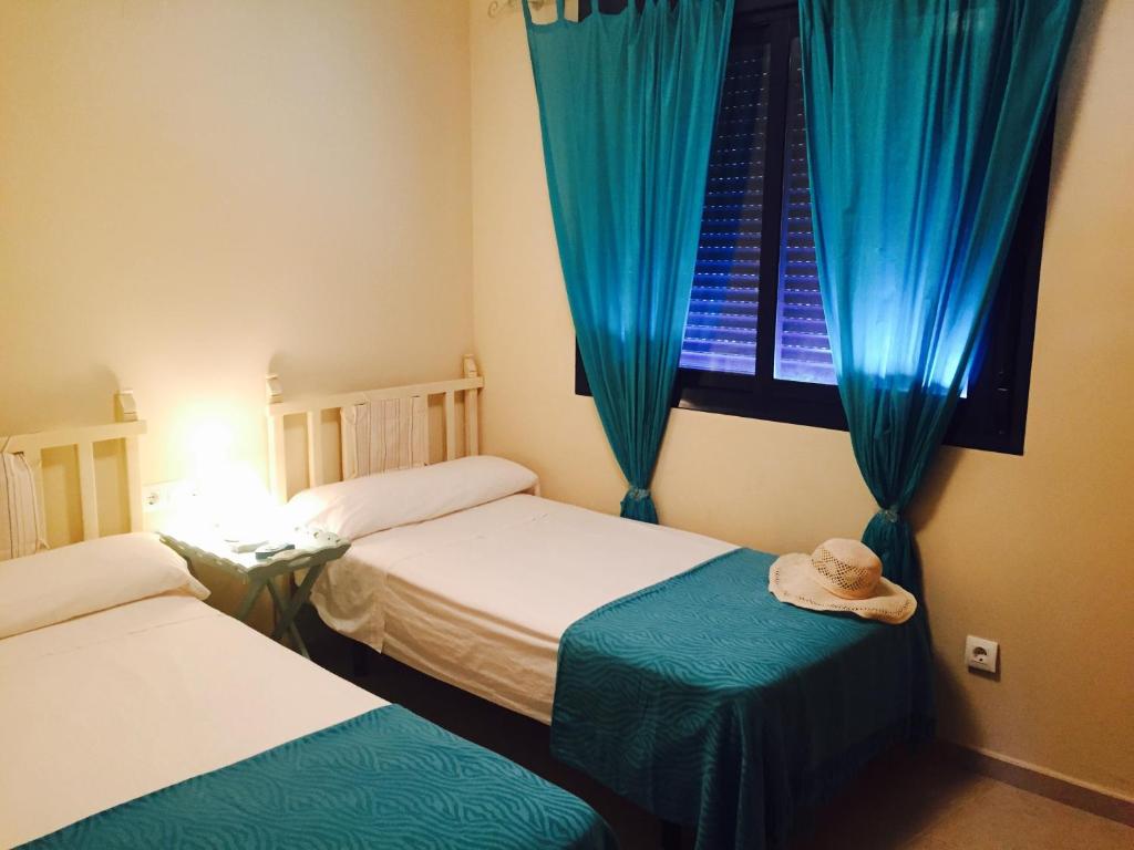 a room with two beds and a window with blue curtains at Sueño de Mar in Denia