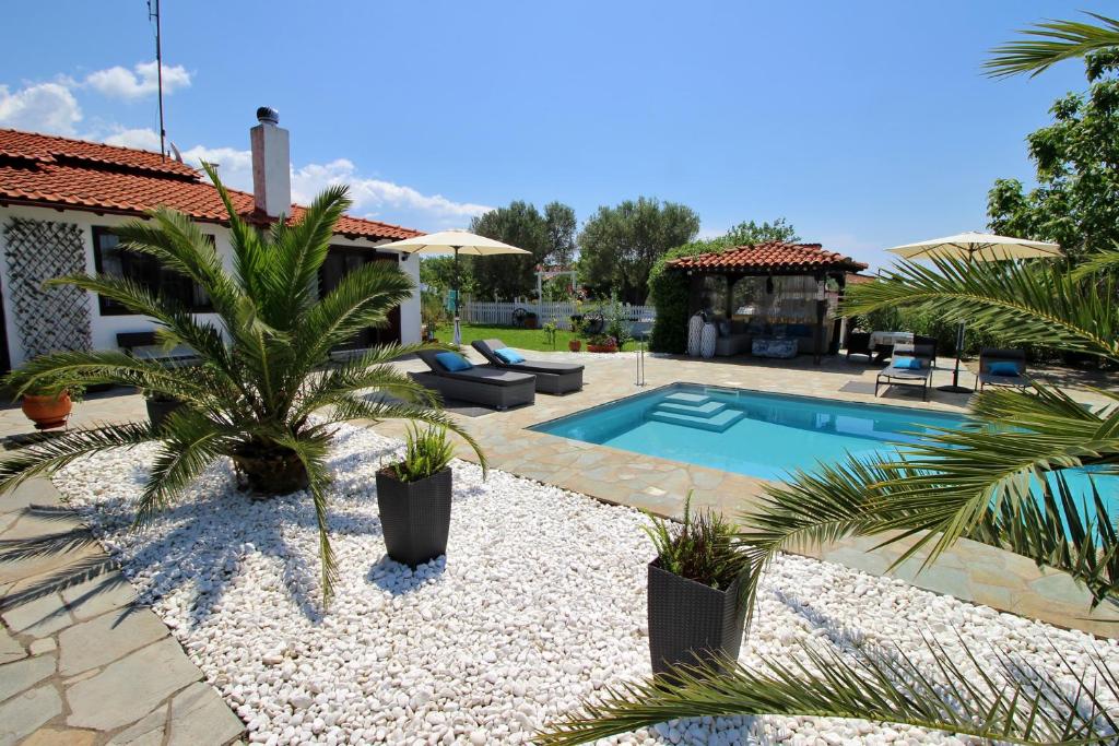 a backyard with a swimming pool and palm trees at Casa Mary di Mare in Epanomi