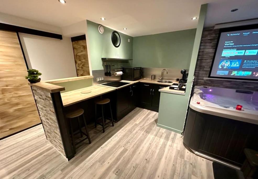 a large kitchen with a bar and a large screen at Appartement Love Room/Jacuzzi in Toulouse